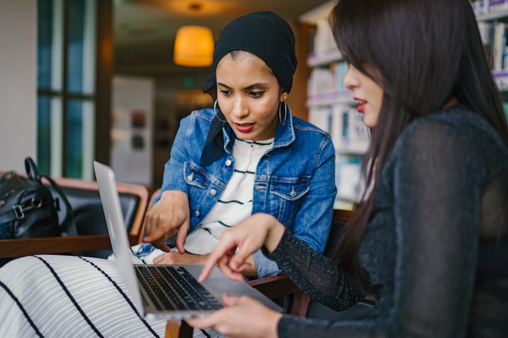 Two women looking at a computer and considering local SEO