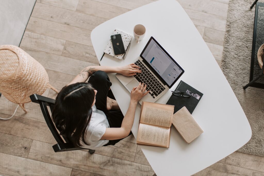 Top-down view of a woman working on remarketing campaigns on a laptop at a white desk